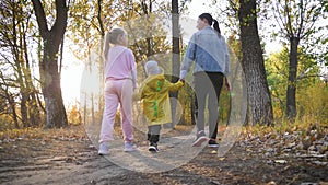 Mother and two children walking in the park and enjoying the beautiful autumn nature. Happy family on autumn walk.