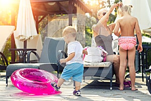 Mother with two cute caucasian blond little siblings children enjoy having fun vacation on poolside near pool or sea