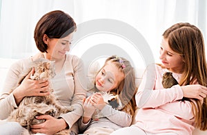 Mother and two daughters holding their favorite pets on hands.