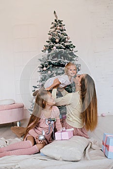 Mother and two daughters playing at home near Christmas tree. happy family have fun for the Christmas holidays