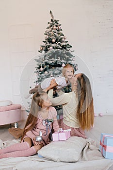 Mother and two daughters playing at at home near Christmas tree. happy family have fun for the Christmas holidays