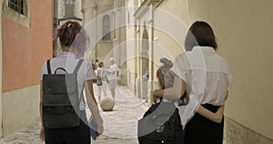 Mother and two daughters students walking together, back view