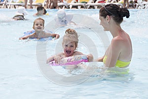 A mother and two daughters are swimming in a public pool