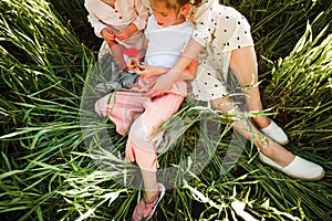 A mother with two daughters is walking in a green field. Hugs and feelings.