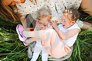 A mother with two daughters is walking in a green field. Hugs and feelings.