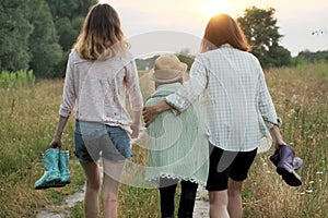 Mother and two daughters walking together along country road