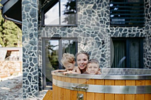 Mother with two kids playing in the water, in outdoor hot tub. Brother and sister enjoying summer time in outdoor pool