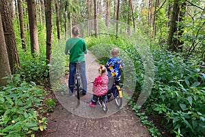 Mother with two kids riding bikes in forest