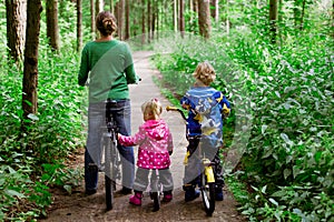 Mother with two kids riding bikes in forest