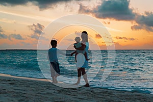 mother and two kids walking at sunset beach