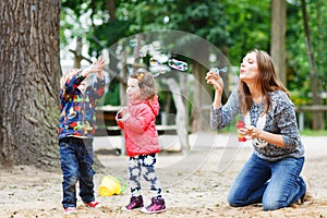 Mother and two little children playing together on playground