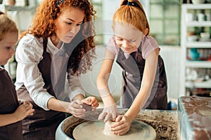 Mother and two redhead daughters made clay cup with pottery wheel
