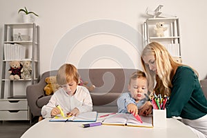 Mother and two son together draw, paint. Mom helps the children boys. Teacher mom working with creative kids. Children