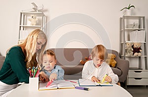 Mother and two son together draw, paint. Mom helps the children boys. Teacher mom working with creative kids. Children