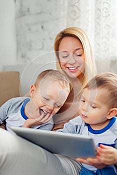 Mother with two sons playing with digital tablet at home