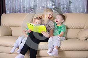 Mother and two sons are reading a book.