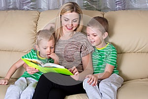 Mother and two sons are reading a book.