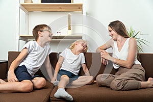 Mother and two sons are sitting on couch and have fun talking. Family friendly relations photo