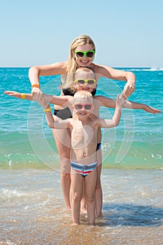 Mother and two sons in sunglasses resting and playing on the beach..Summer family vacation.