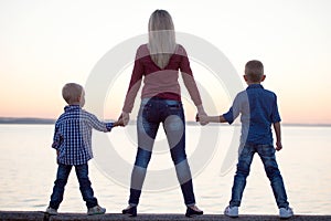 Mother and two sons walk on the promenade and watch the sunset