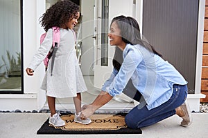 Mother Tying Daughters Shoelaces As She Leaves For School