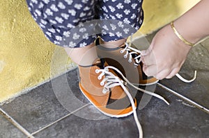 Mother is tying her daughter shoes