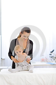 Mother undressing baby at pediatricians cabinet photo