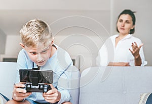 Mother unhappy with teenager son who spent his free time with electronic devices and games photo