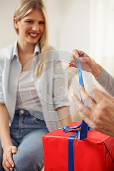 Mother unwrapping gift box she has just received from her daughter. Mother`s day. Happy family moments at home. Selective focus
