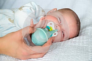 Mother using bulb syringe to clean baby's nose