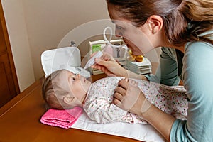 Mother using the nasal aspirator with her baby