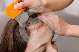 Mother using nit comb on her daughter`s hair. Anti lice treatment photo