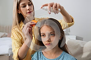 Mother using nit comb and spray on hair at home. Anti lice treatment photo