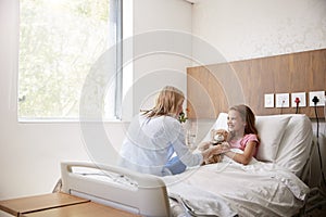 Mother Visiting Daughter Lying In Bed In Hospital Ward