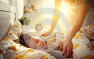 Mother wakes up sleeping child daughter girl in morning