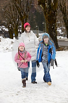 Mother Walking Two Children To School In Snow