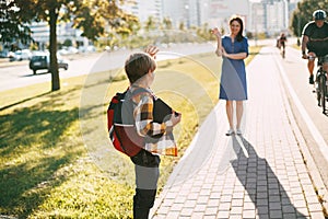 A mother walks her son to school. Mom Waves goodbye to the boy, and he waves back. The concept of training and education, a place