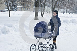 Mother walks with a stroller on a snowy winter day