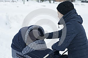 Mother walks with a stroller on a snowy winter day