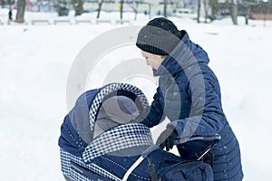 Mother walks with a stroller on a snowy winter day