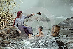 Mother was showering for a baby daughter. At a stream in a rural area of Thailand
