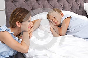 Mother watching her son sleep in bed