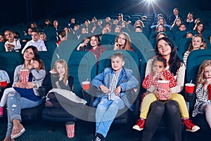 Mother watching movie with little children on first cinema row.
