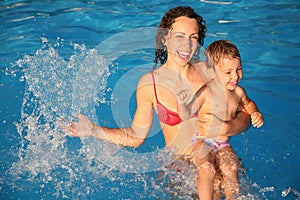 Mother in water with child makes heart with drops