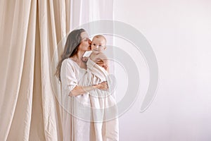 Mother in white clothes kiss a baby. Purity innocence sanctity of motherhood.