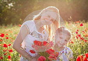 Mother in white with daughter together on blossoming red poppies field