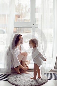 mother in a white robe sits with a child a blonde daughter