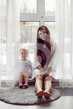 mother in a white robe sits with a child a blonde daughter