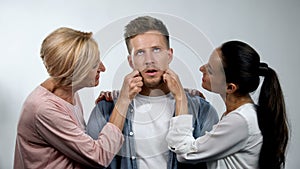 Mother and wife admiring mature man and pinching cheeks, overprotection concept
