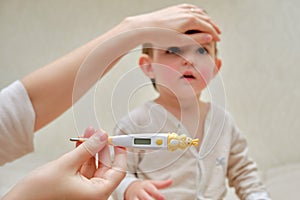 A mother woman measures the temperature of a sick toddler baby wit